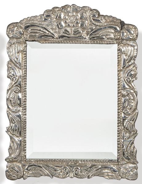  Espejo de pared con alma de madera y plata boliviana repujada y cincelada con motivos florales y querubines en las esquinas.