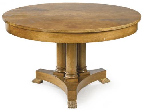  Mesa comedor redonda estilo imperio en madera de nogal, sobre pedestal formado por cuatro columnas clásicas torneadas y plataforma de lados cóncavos apoyada sobre patas en forma de garra. S. XX