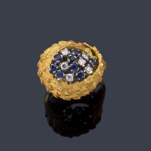  Anillo con centro de zafiros y brillantes sobre montura con diseño vegetal texturizado de oro amarillo de 18K.