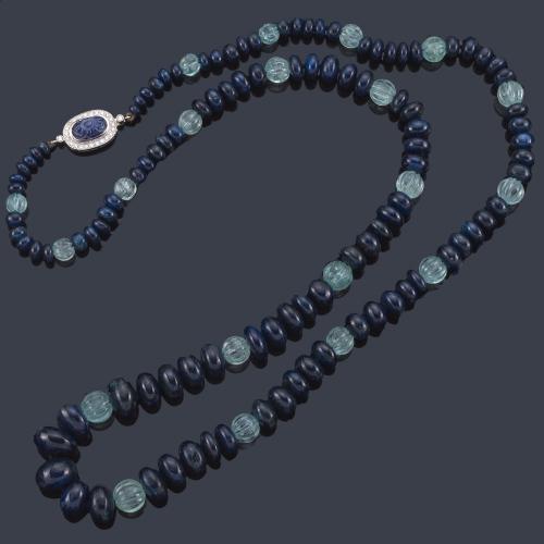 Lote 2199
LUIS GIL
Collar largo con cuentas de zafiros y aguamarinas gallonados con cierre ovalado de oro blanco de 18K con pieza tallada de zafiro y orla de brillantes.