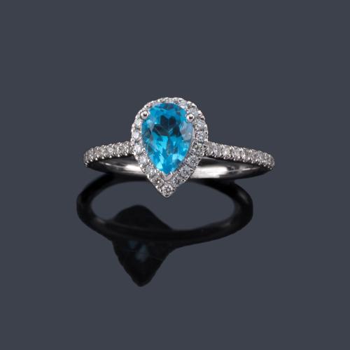  Anillo con topacio azul talla perilla de aprox. 1,05 ct con orla y brazos de brillantes de aprox. 0,23 ct en total.