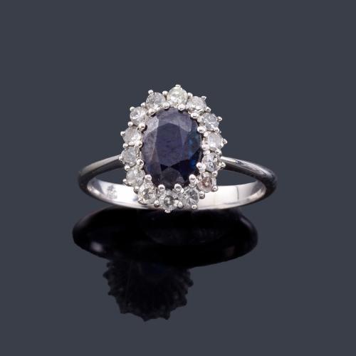  Anillo con zafiro talla oval de aprox. 0,75 ct con orla de brillantes en montura de oro blanco de 18K.