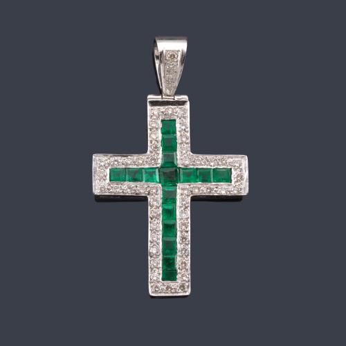  Cruz con esmeraldas calibradas y orla de brillantes en montura de oro blanco de 18K.