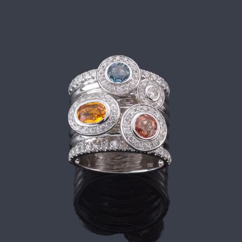  Anillo ancho con gemas de color y orla de brillantes en montura de oro blanco de 18K.