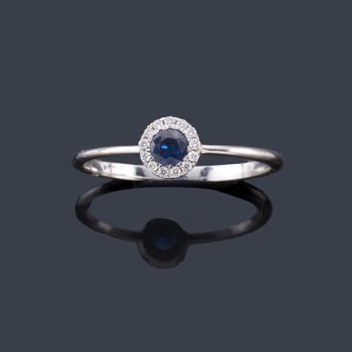 Lote 2319
Anillo con zafiro central de aprox. 0,23 ct con orla de brillantes en montura de oro blanco de 18K.