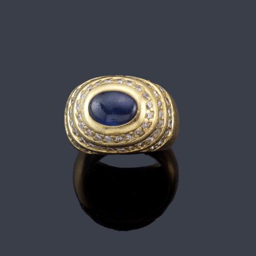  Anillo con zafiro talla cabujón con tres orla de brillantes en montura de oro amarillo de 18K.