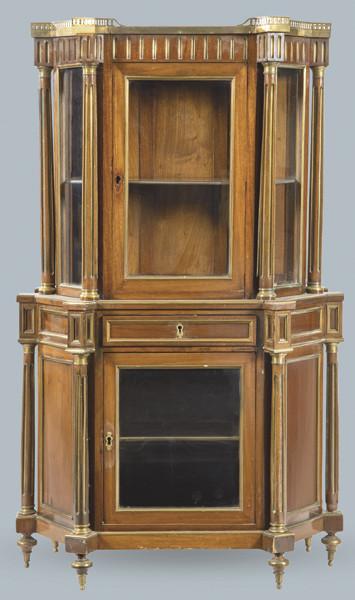  Vitrina estilo directorio en madera de caoba de forma poligonal con columnas clásicas de dos cuerpos y aplicaciones en metal dorado. Tapa superior en mármol blanco.