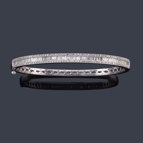  Pulsera rígida con banda central de diamantes talla baguette y brillante, en montura de oro blanco de 14K.