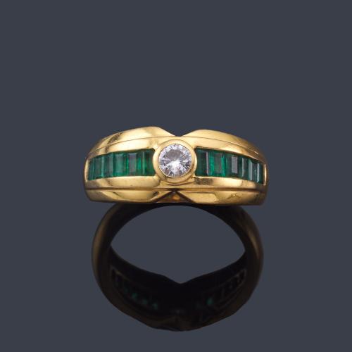  Anillo con brillante central de aprox. 0,20 ct con banda de esmeraldas calibradas en ambos lados.