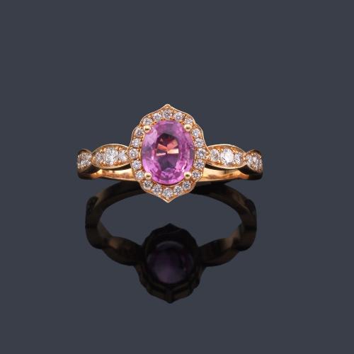  Anillo con zafiro rosa talla oval de aprox. 1,00 ct con orla y brazos de brillantes de aprox. 0,40 ct en total.