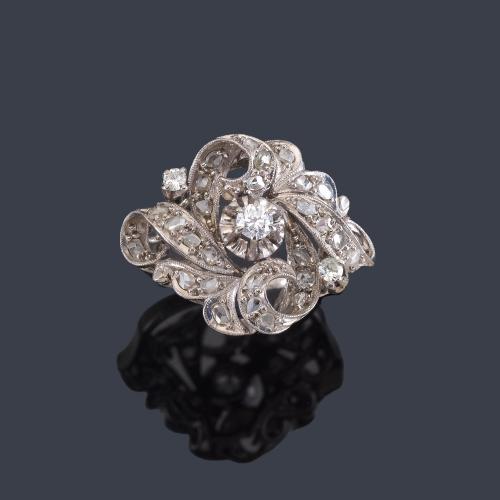 Lote 2461
Anillo con diseño de roleos con brillante central de aprox. 0,20 ct y diamantes talla rosa, en montura de oro blanco de 18K.