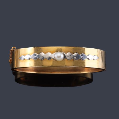 Lote 2477
Pulsera ancha rígida con perlita central y detalle en oro blanco, realizada en oro amarillo de 18K.