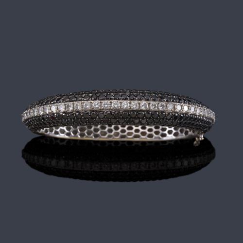 Pulsera rígida con banda central de brillantes incoloros y pavé de diamantes negros en ambos lados sobre montura de oro blanco de 18K.