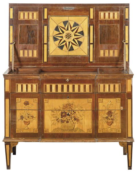 Cómoda secreter época Carlos IV, de cuerpo prismático, realizada en madera de caoba, nogal, arce y limoncillo, sigue los modelos parisinos de finales del S. XVIII.