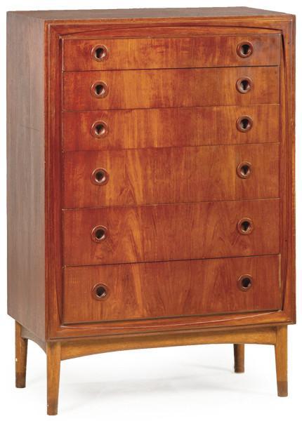  Cómoda alta en madera de teca, con seis cajones largos dentro de un marco moldurado, con tiradores en circulares y patas torneadas.