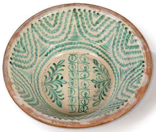 Lebrillo en cerámica esmaltada en verde de fajalauza con decoración de helechos y motivos geométricos en el asiento y cenefa a modo de cortinaje en el alero. 