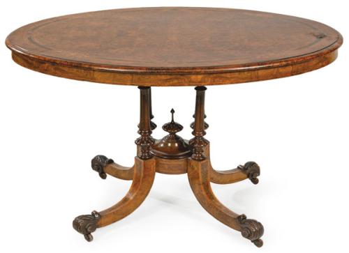 Mesa de centro victoriana, con tapa ovalada en madera de nogal con decoración de marquetería. Sobre pedestal con montantes torneados y patas de sable con decoración tallada. Inglaterra, mediados S. XIX