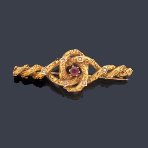 Broche con diseño enroscado con centro de vidrio rojo con decoración de perlitas aljofar en montura de oro amarillo de 18K. Finales S. XIX.
