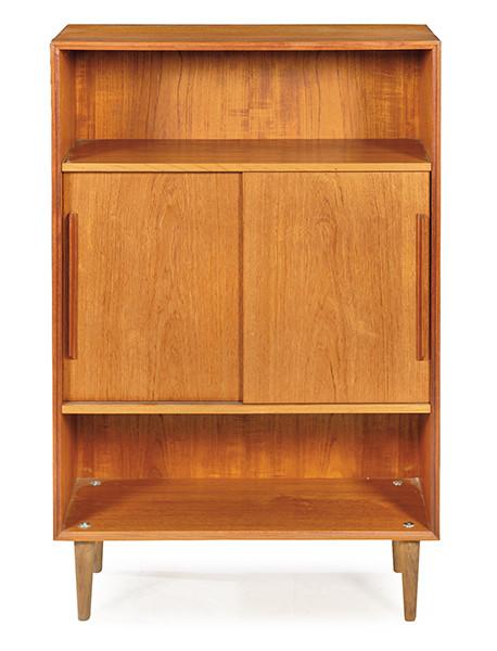 Libreria en madera de teca, compuesta por una parte superior e inferior para libros, y una parte central con dos puertas correderas que se abren para revelar un espacio de almacenamiento.