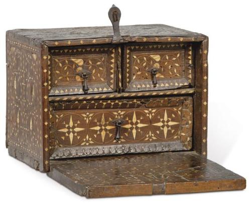  Arquilla con tapa en el frente en madera de nogal, con decoración embutida de hueso y boj. El interior, con gavetas cortas sobre una larga. Tiradores y cerradura de hierro. Faltas.