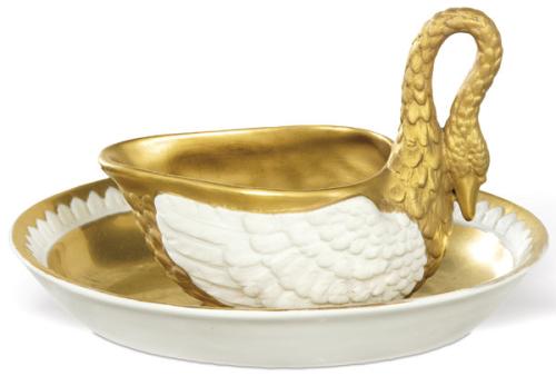  Taza salsera Carl Thieme de Postchappel Dresden en forma de cisne. Esmaltada en blanco y parcialmente dorada. Acompañada de un plato oval a juego esmaltado y dorado. Ambas piezas cuentan con firma en la base. Alemania, principios del siglo XX.