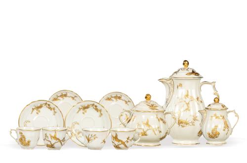 Juego de café de 18 servicios Reine Elisabeth, en porcelana Bernardaud & Compañía de Limoges, con fondo crema decorado con vegetación y pájaros del paraiso en dorado.