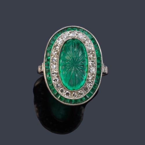 Anillo con esmeralda central cabujón cincelada en motivos vegetales de aprox. 5,80 ct con doble orla de diamantes talla 8/8 y esmeraldas calibradas.