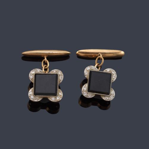 Gemelos 'art decó' con placa de ónix y semiorla de diamantes talla rosa, en montura de oro amarillo de 18K y vista en platino. Años '30.