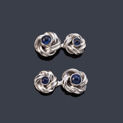 Gemelos con diseño de nudo y zafiro central talla cabujón, en montura de oro blanco de 18K.