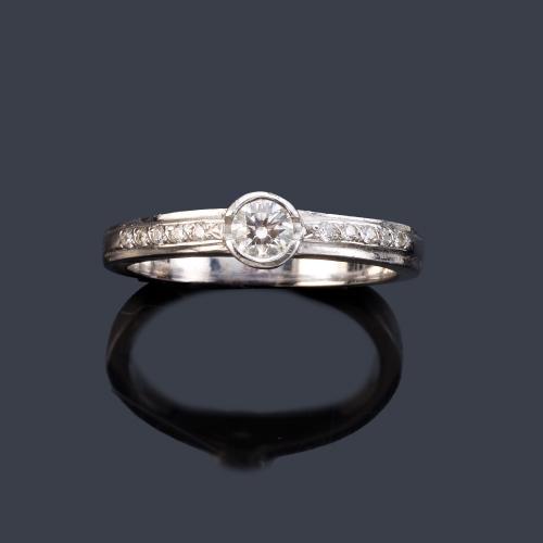 Anillo con brillante central de aprox. 0,20 ct con banda de brillantitos en ambos lados.