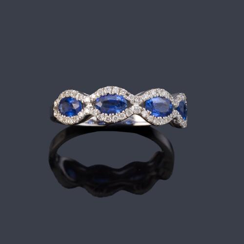 Anillo con cuatro zafiros talla oval con orla ondulada de brillantitos en montura de oro blanco de 18K.