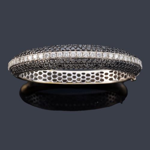 Pulsera rígida con banda central de brillantes incoloros y pavé de diamantes negros en ambos lados sobre montura de oro blanco de 18K.