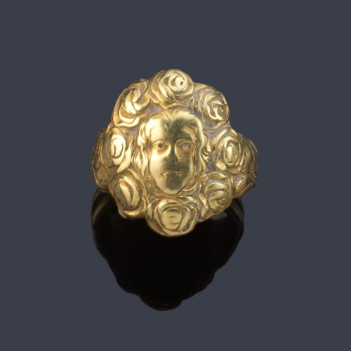 Anillo con rostro femenino con orla de rosas cincelado en oro amarillo de 18K.