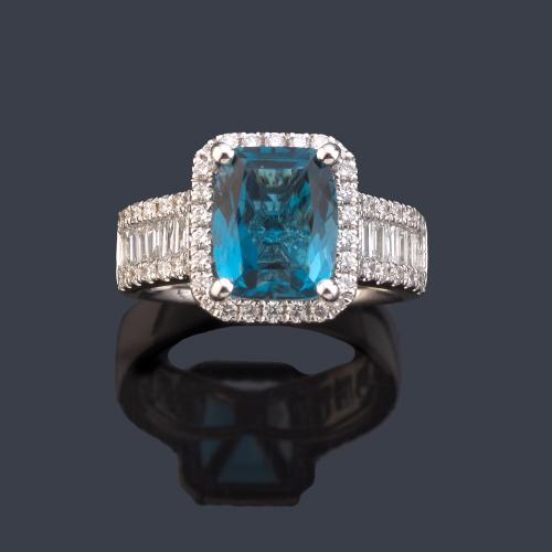 Anillo con topacio azul central de aprox. 3,80 ct con orla y banda de diamantes talla brillante y baguette de aprox. 0,94 ct en total.