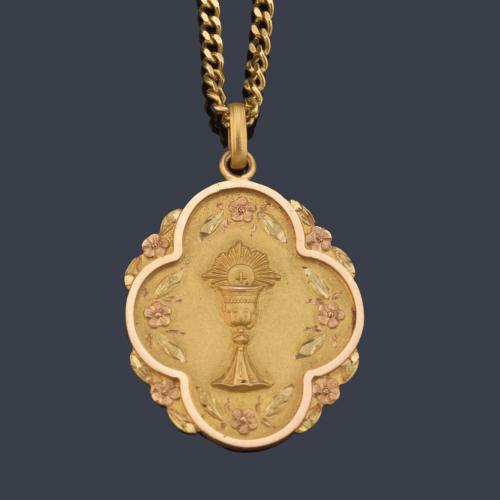 Medalla con motivo de cáliz cincelado y orla de motivos florales en montura y cadena de oro amarillo de 18K. Circa 1912.