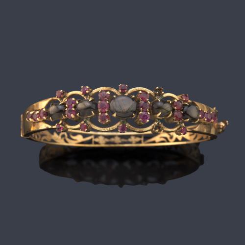 Pulsera rígida con frente de crisoberilos talla cabujón y rubíes en montura de oro amarillo de 14K. Ppios S. XX.