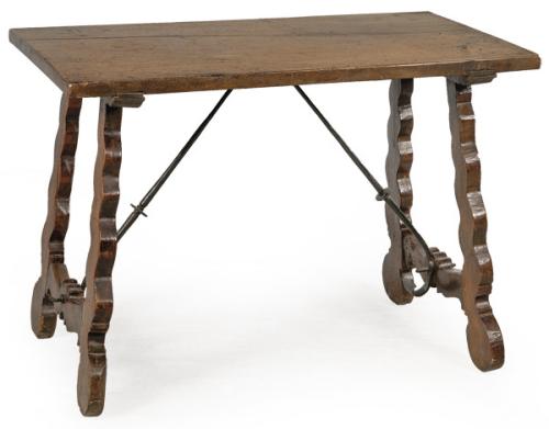 Mesa con tapa rectangular en madera de nogal, sobre patas recortadas y fiadores de hierro abalaustrados. 