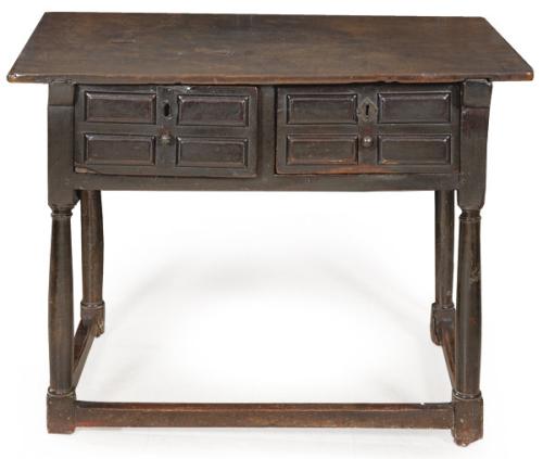 Bufete en madera de nogal. De cubierta rectangular, al frente, en la cintura, dos cajones moldurados. Sobre montantes torneados en forma de columna toscana con fuste liso unidas por chambranas rectas.