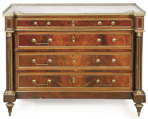 Cómoda Luis XVI en madera de caoba. Sobre patas cónicas descansa un cuerpo con cuatro cajones largos superpuestos, flanqueados por columnas de fuste estriado, con tiradores en latón. Cubierta en mármol blanco.