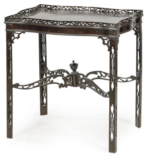 Mesa de té estilo Chippendale, con tapa de perfil sinuoso ornamentada con una balaustrada calada. Sobre patas rectas unidas por una chambrana en cruz recortada.