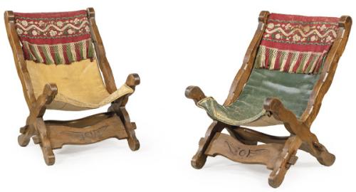 Pareja de butacas con estructura de madera recortada y asiento de cuero.