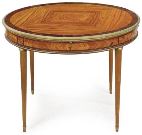 Mesa auxiliar estilo directorio, con tapa circular en madera de palo de rosa y palo santo sobre patas cónicas y monturas de bronce.