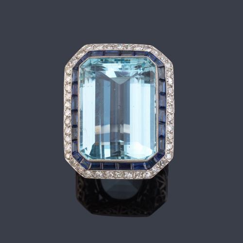 Anillo con gran aguamarina de aprox. 40,00 ct con orla de zafiros calibrados de aprox. 1,00 ct y brillantes de aprox. 1,78 ct en total.