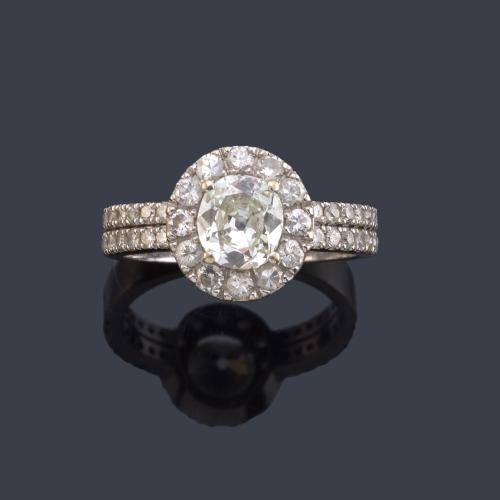 Solitario con diamante central talla oval de aprox. 0,90 ct con orla y brazos con brillantes de aprox. 0,68 ct en total.