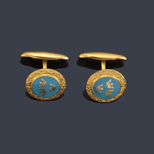 Gemelos con motivo de tres coronas sobre esmalte azul en metal dorado.