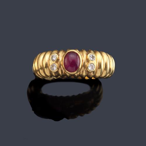 Anillo con rubí talla cabujón con brillantes en ambos lados, realizado en montura de oro amarillo de 18K.