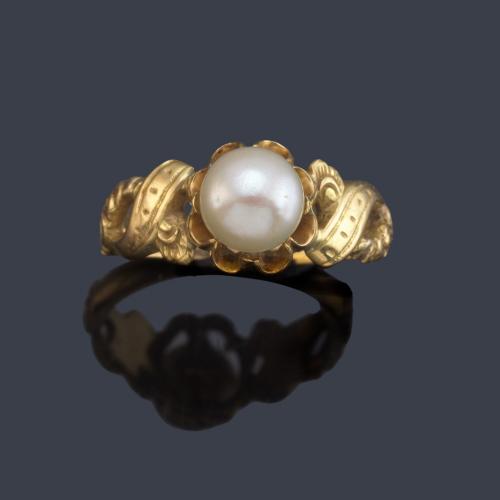 Anillo con perla central en montura de oro amarillo de 18K.
