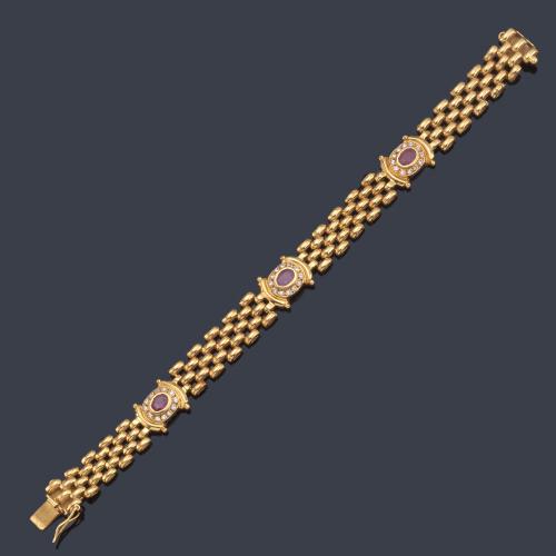 Pulsera con tres motivos ovalados con rubíes con orla de piedras incoloras, en montura de oro amarillo de 18K.