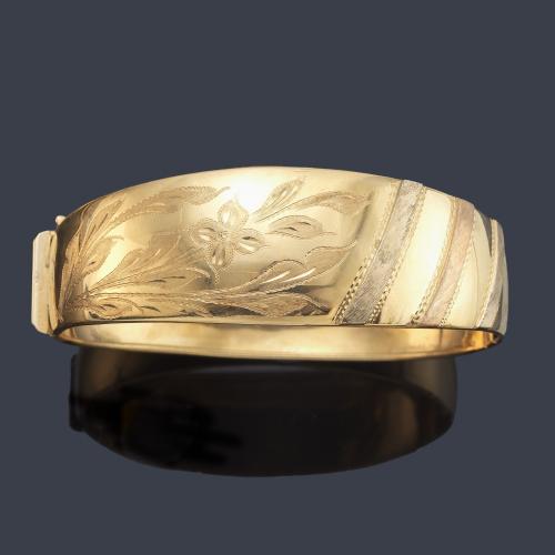 Pulsera rígida con detalles vegetales cincelados en montura de oro amarillo de 18K.