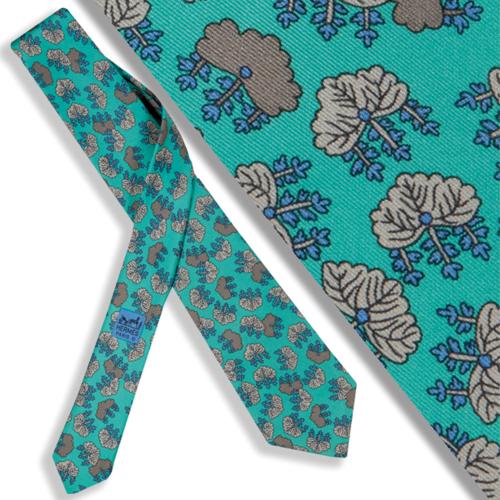Corbata Hermés con motivos de hojas sobre fondo turquesa